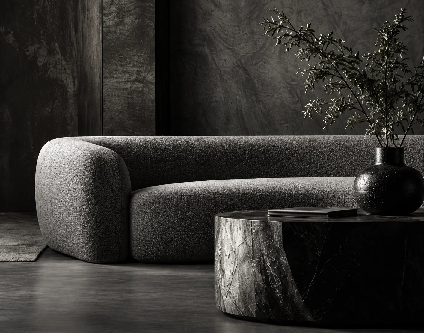 A sculptural charcoal sofa in a dark, textured interior
